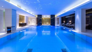 A modern indoor swimming pool with a starry ceiling design, a reception area, and lounge seating. - Hilton Kyiv (Kyiv)