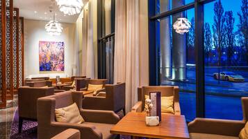 A modern hotel lobby with seating areas, large windows, and decorative lighting.