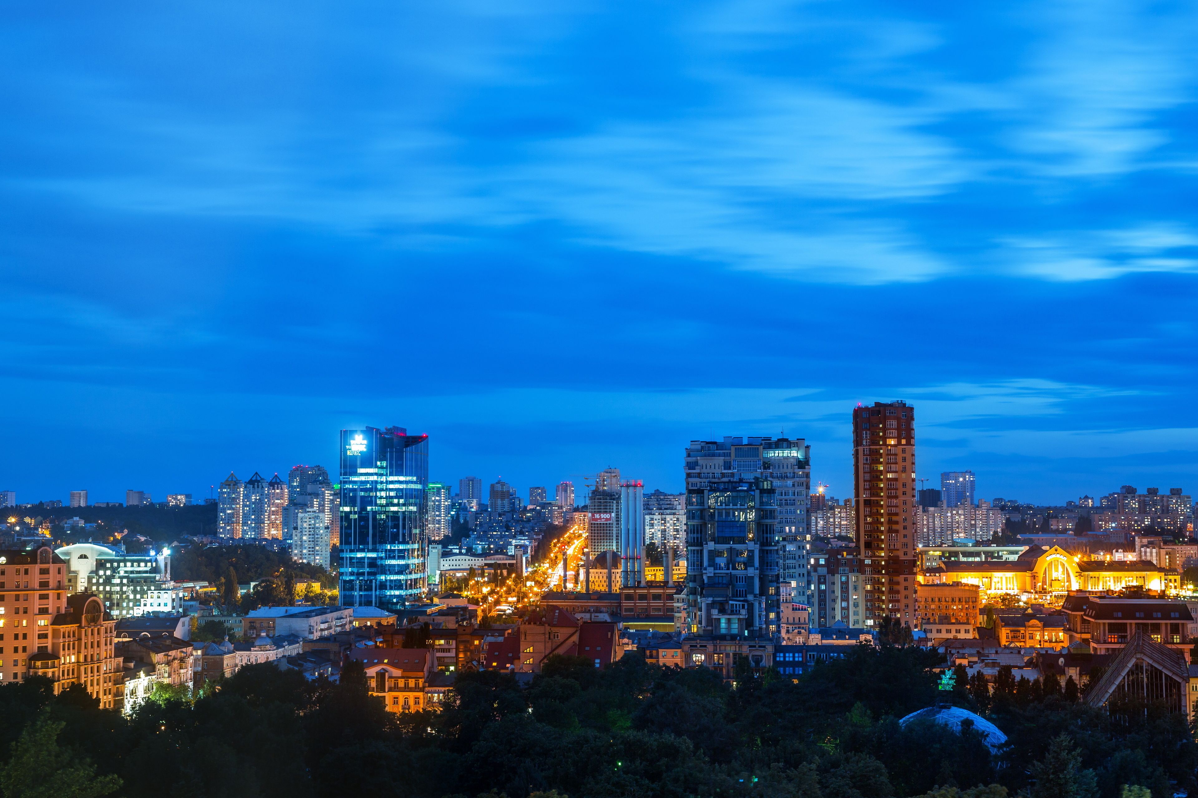 A cityscape at dusk with illuminated buildings and a clear sky.