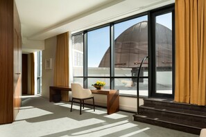 A hotel room with a large window, a desk, a chair, and a small table with flowers. - Hilton Kyiv (Kyiv)