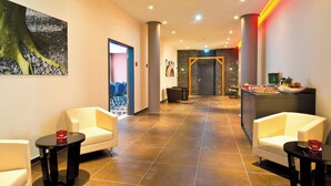 A hotel lobby with seating areas, a reception desk, and a wall-mounted painting. - Leonardo Hotel Völklingen - Saarbrücken (Voelklingen)