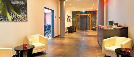 A hotel lobby with seating areas, a reception desk, and a wall-mounted painting.