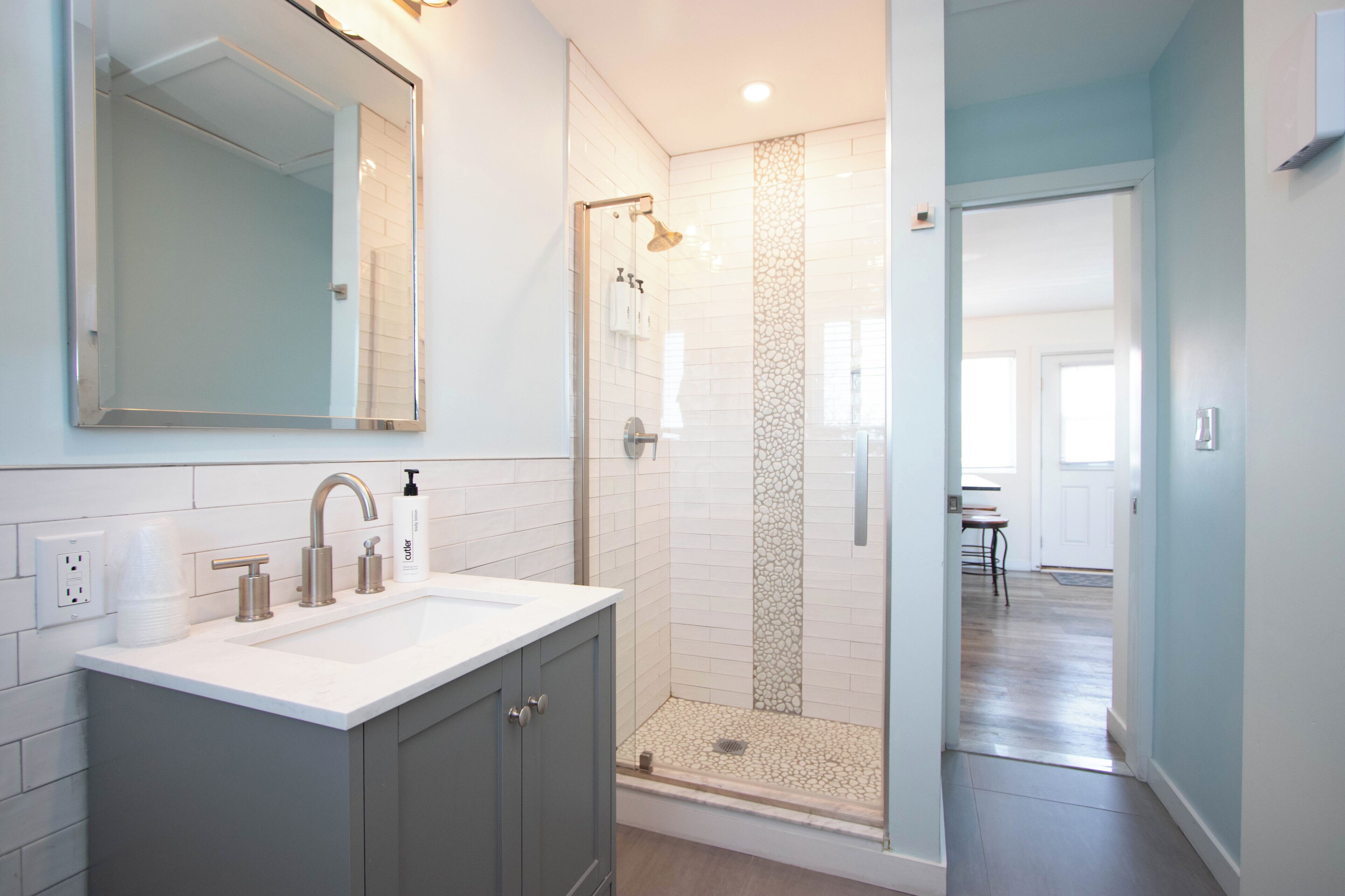 Een badkamer met een douche met glazen wand, een wastafel met spiegel en een toilet.