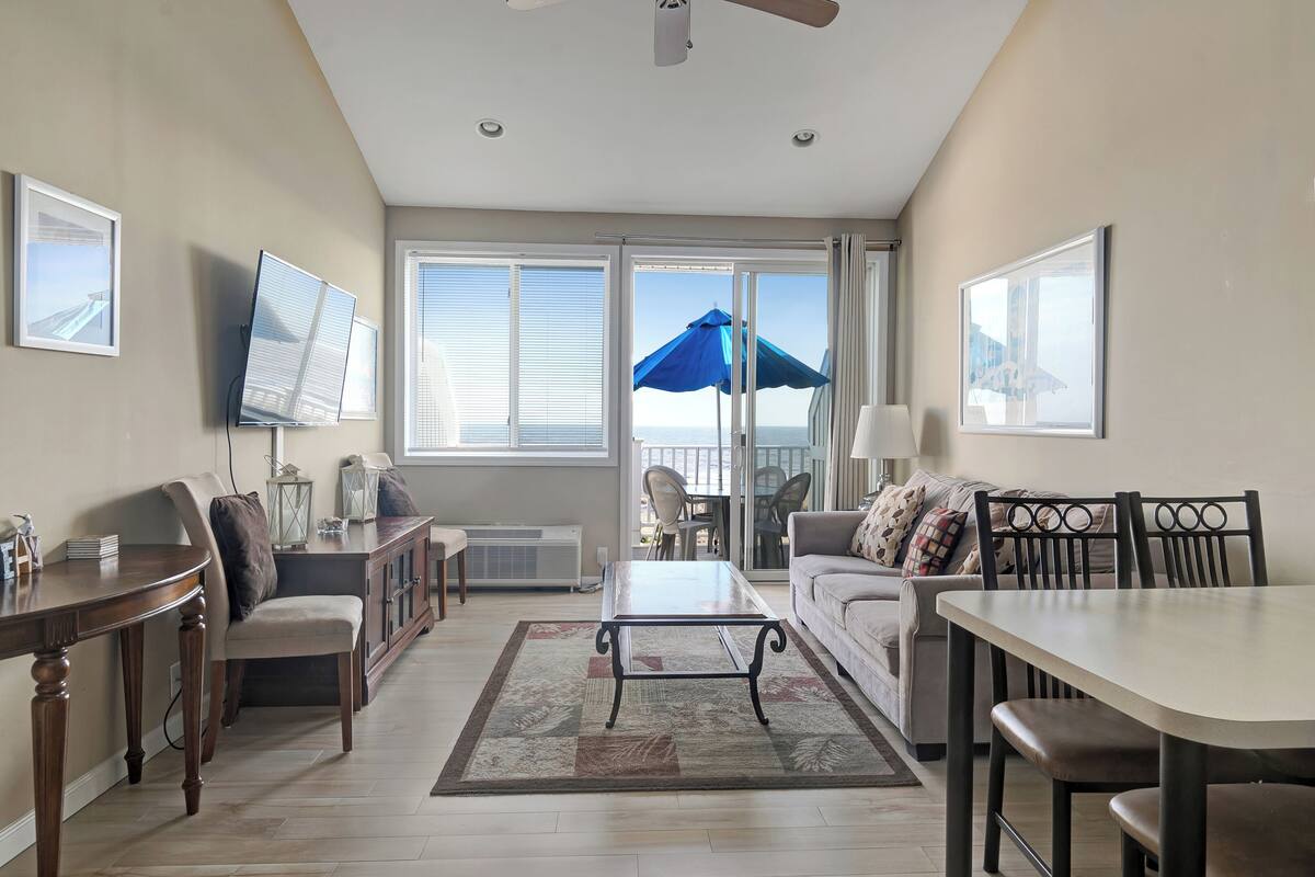 A living room with a sofa, chairs, a coffee table, a TV, and a view of the outdoors.
