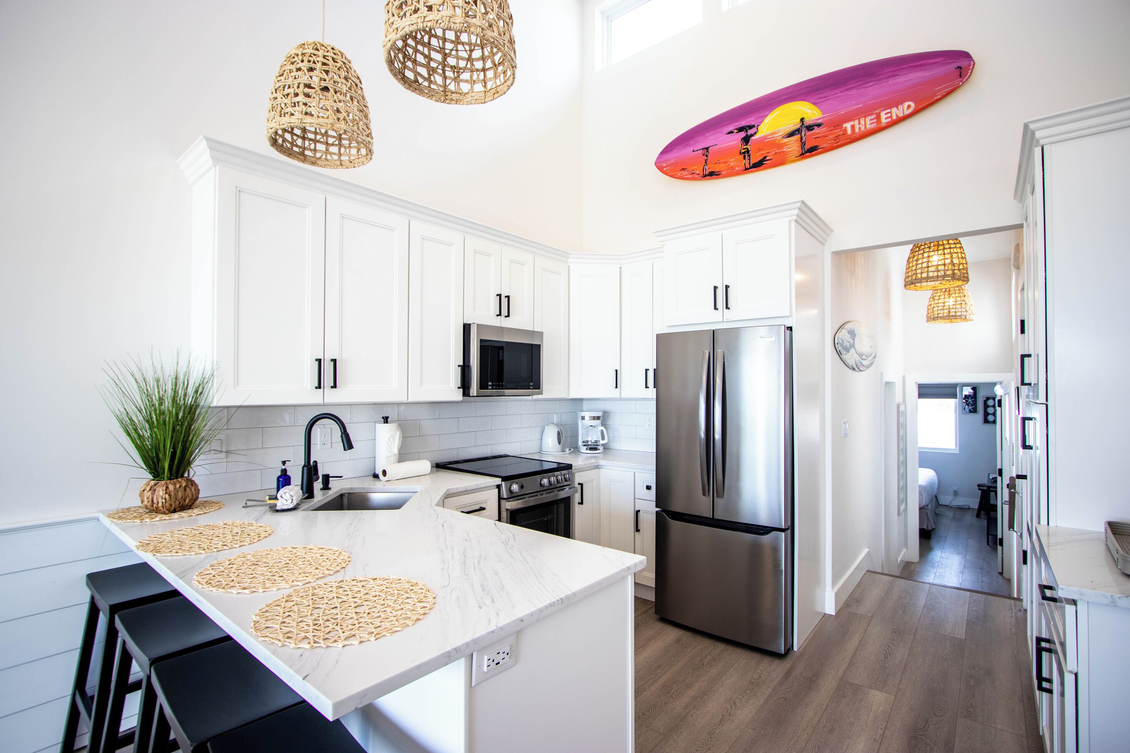 Una cocina moderna con armarios blancos, electrodomésticos de acero inoxidable y una isla central.