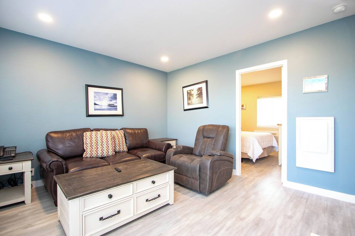 A living room with a brown leather sofa, a recliner, a coffee table, and a white chest of drawers.