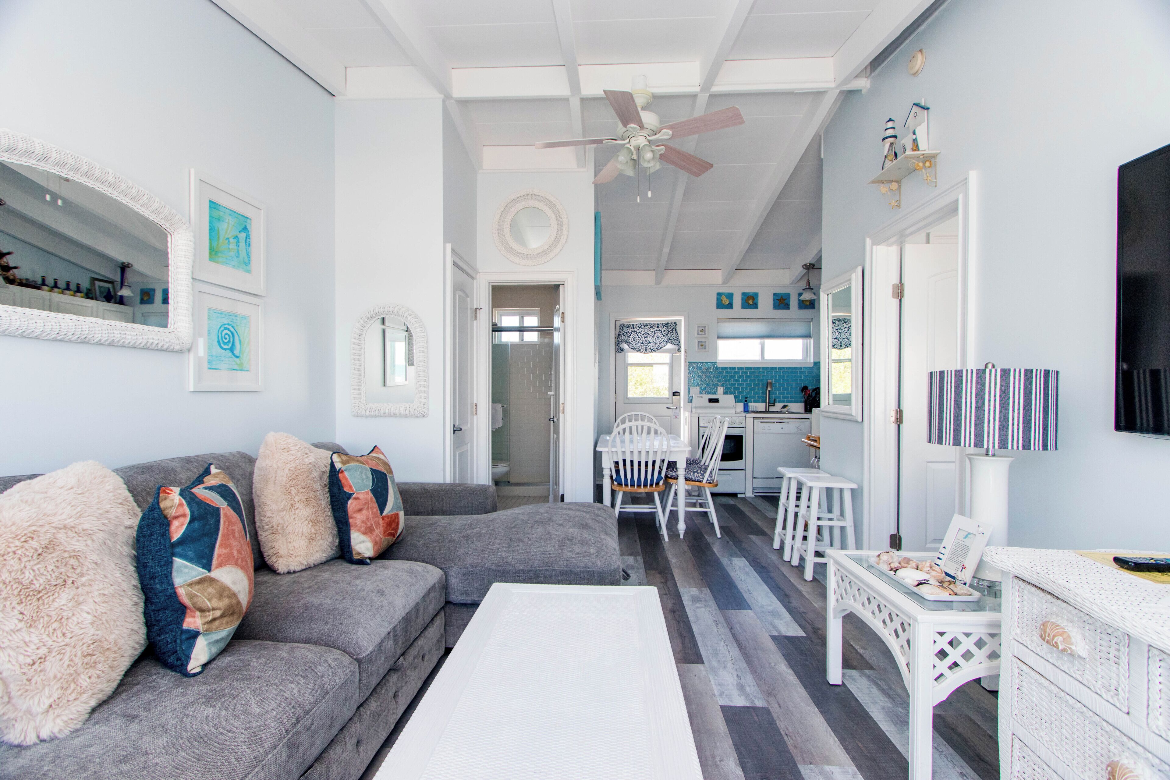 A living room with a grey sofa, a white coffee table, and a ceiling fan.