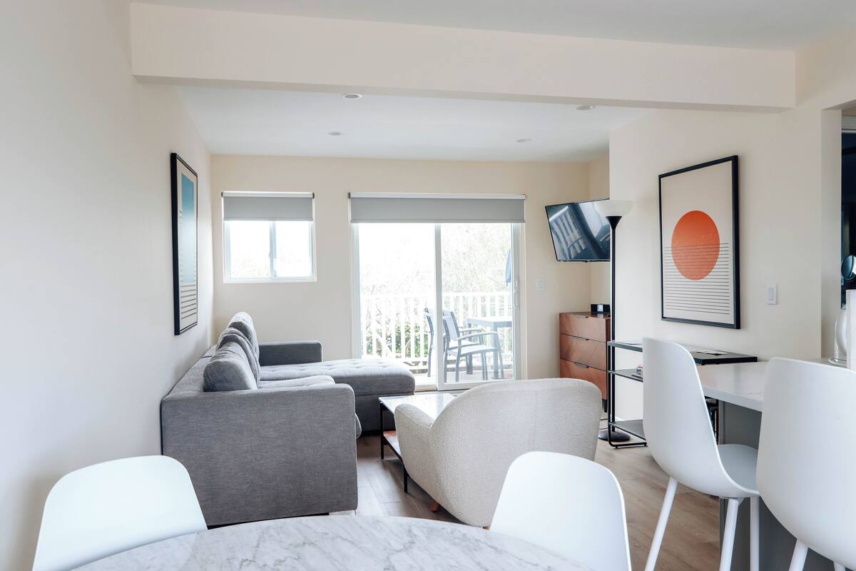 A modern living room with a sofa, chairs, a table, and a TV.