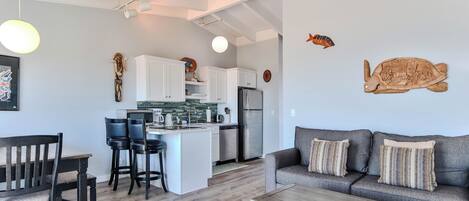 A modern living space with a kitchen, dining area, and a sofa with decorative pillows.