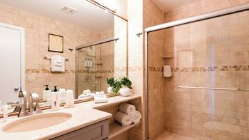 A bathroom with a sink, mirror, shower, and towel rack.