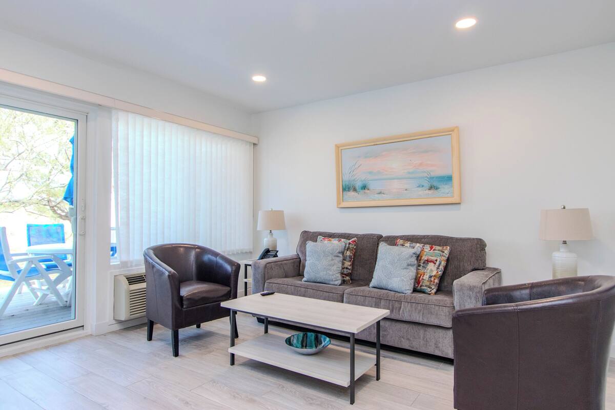 A living room with a sofa, two armchairs, a coffee table, and a painting on the wall.