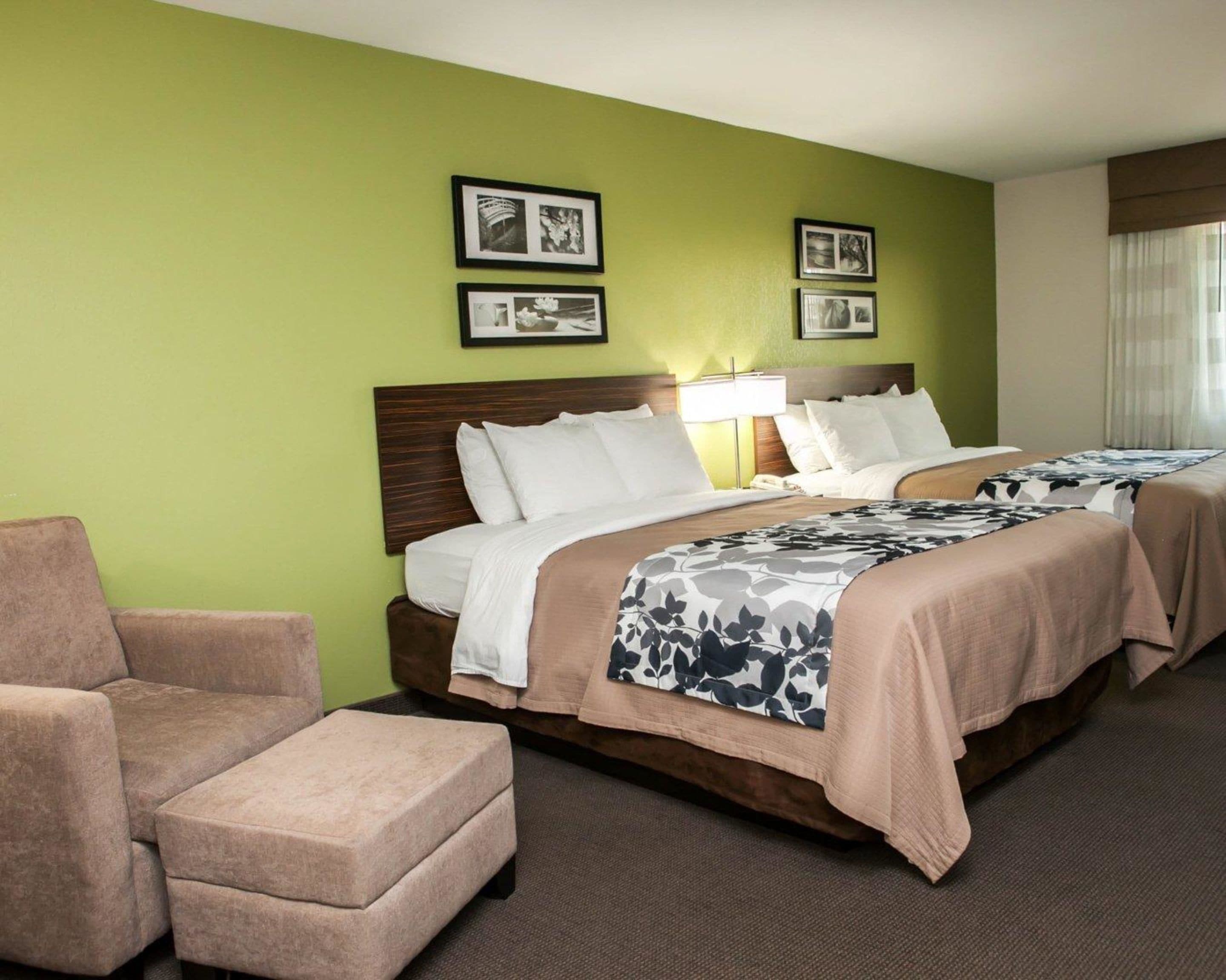 Habitación de hotel con una cama grande, una silla y dos cuadros en la pared.