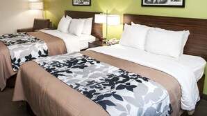 Una habitación de hotel con dos camas, una mesita de noche con lámpara y cuadros en la pared.