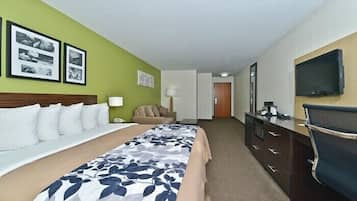 A hotel room with a bed, a desk, a chair, a TV, and a lamp.