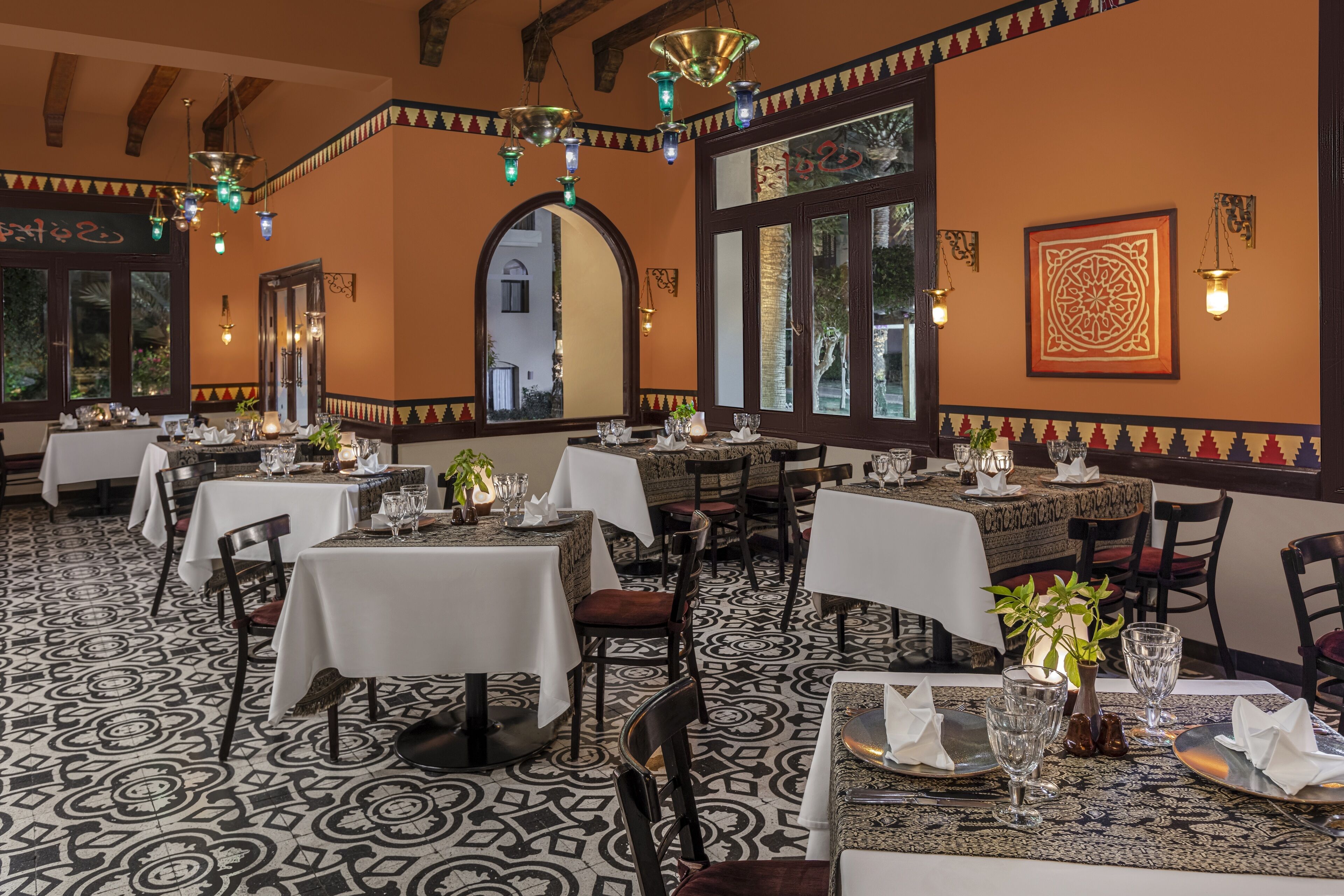 Un restaurante con varias mesas dispuestas para comer, con baldosas de suelo estampadas y decoración tradicional.