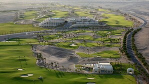 En golfbane med flere bunkers, et klubhus og en parkeringsplads.