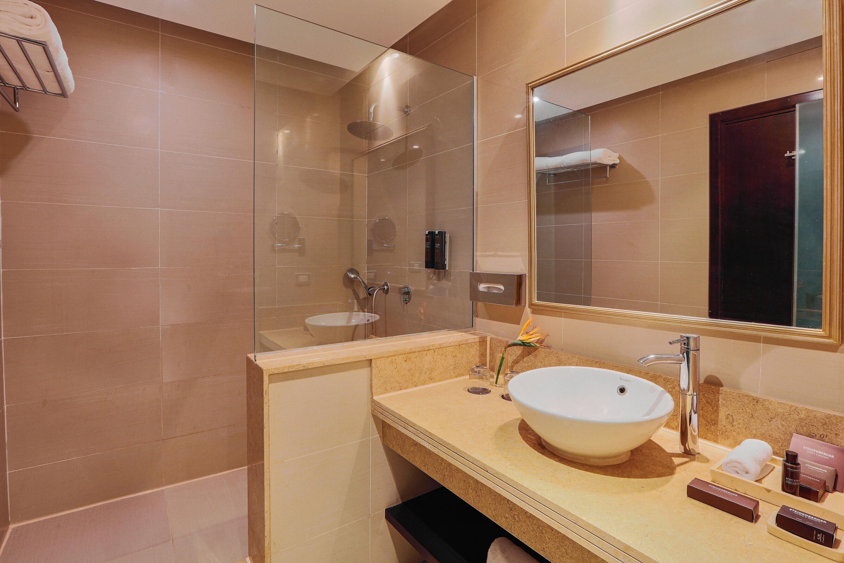 Un baño moderno con cabina de ducha de vidrio, un lavamanos grande y un espejo.