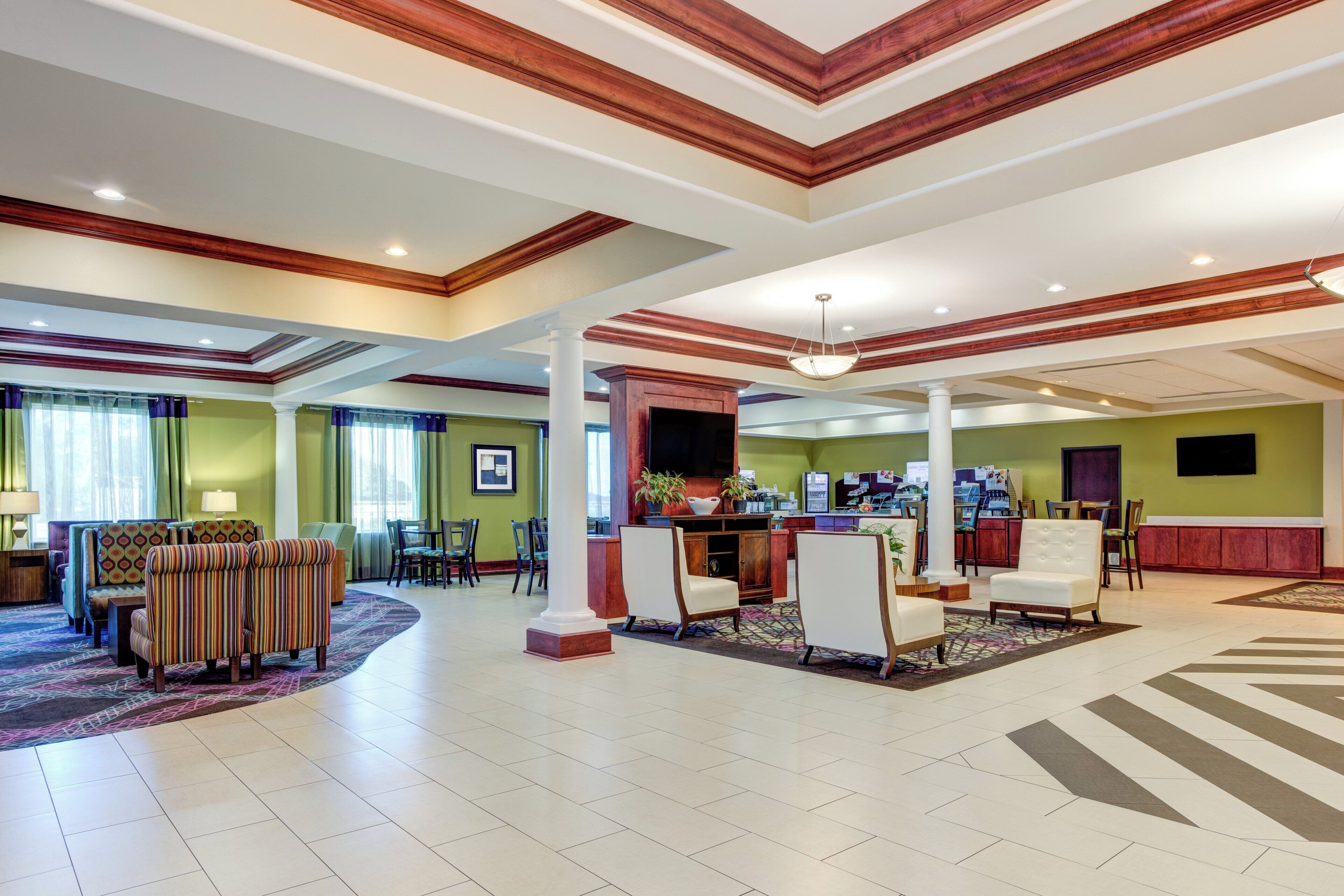 A spacious lobby with a reception desk, seating area, and a large window with curtains.
