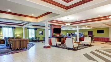 A spacious lobby with a reception desk, seating area, and a large window with curtains.
