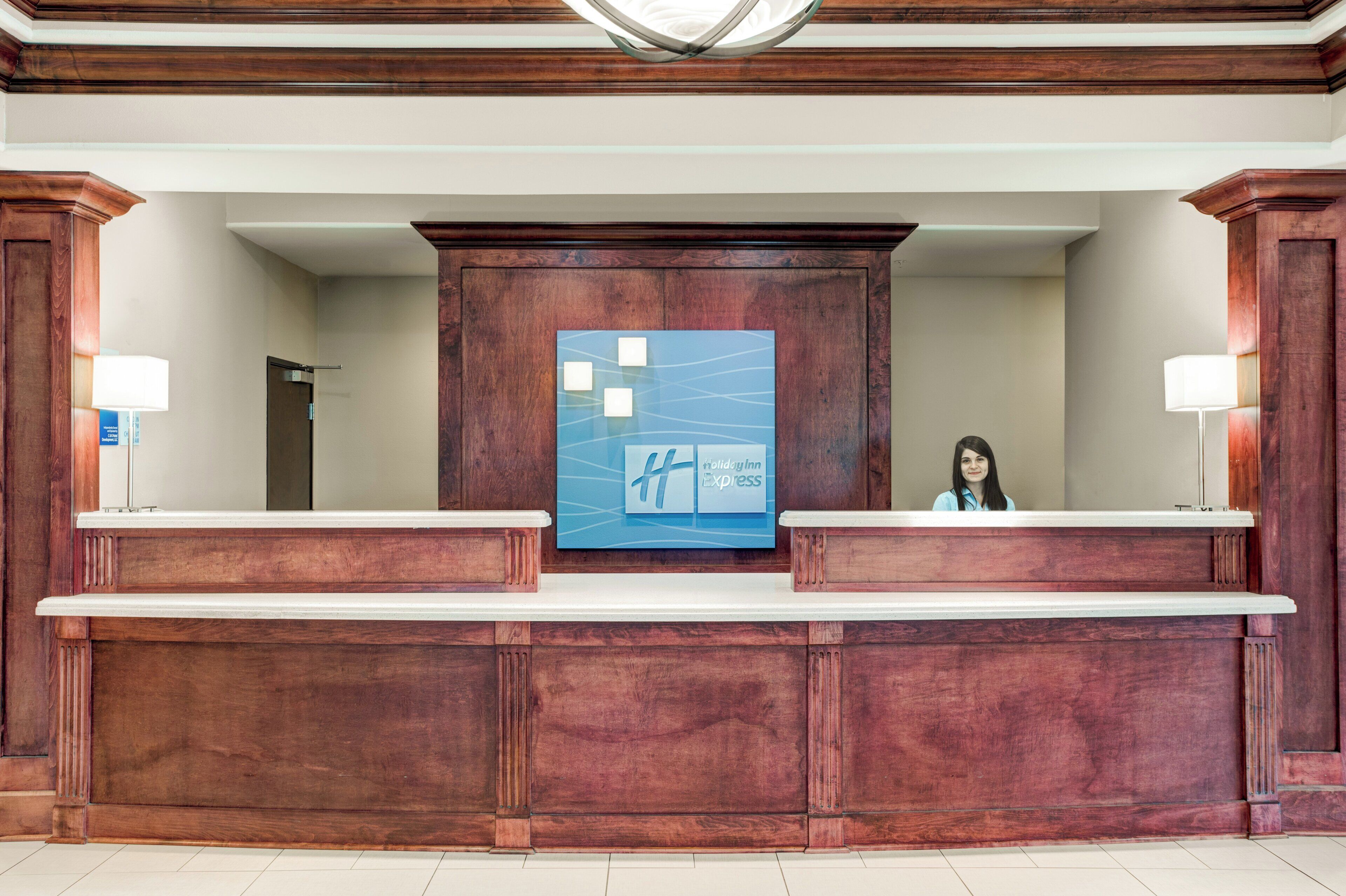 A reception desk with a wooden finish, a large blue sign with text, and two lamps on either side.