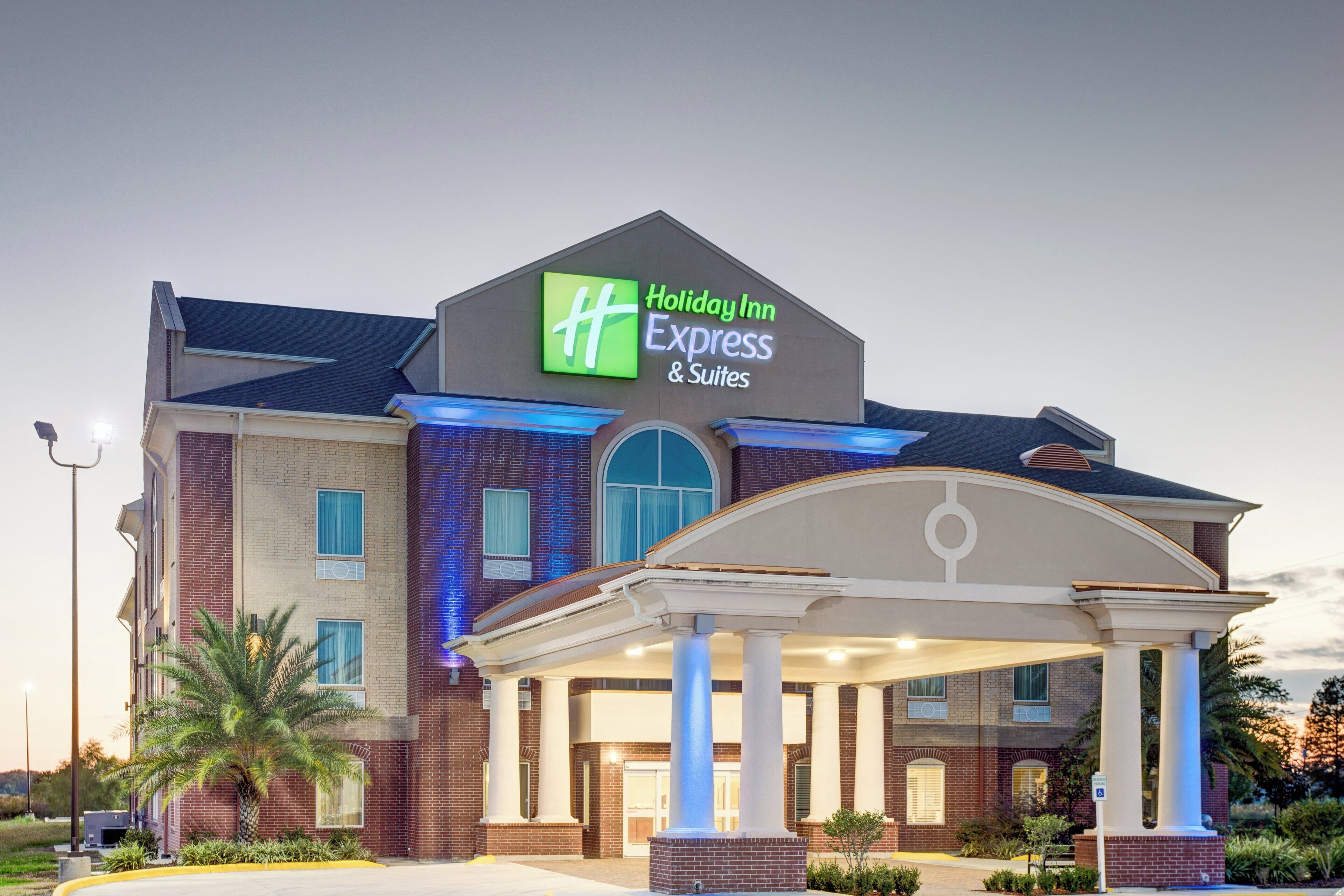 Un bâtiment de la chaîne Holiday Inn Express & Suites, avec une façade en briques, de grandes fenêtres et un espace d’entrée abrité.