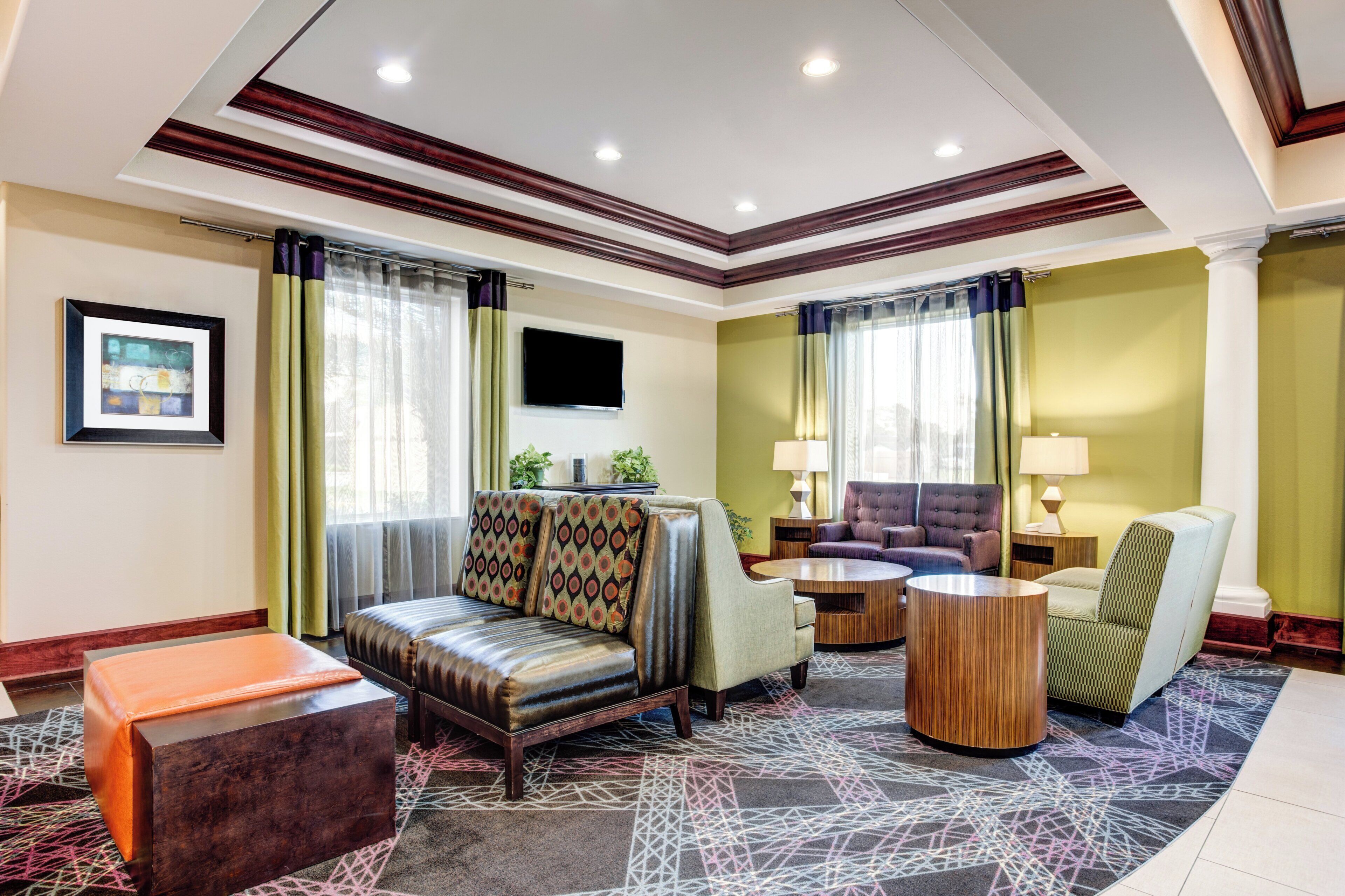 A hotel room with a sofa, armchairs, a coffee table, and a TV.