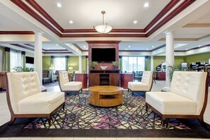 A hotel lobby with a central seating area, a flat-screen TV, and a patterned carpet. - Holiday Inn Express Hotel & Suites Raceland - Highway 90 by IHG (Raceland)