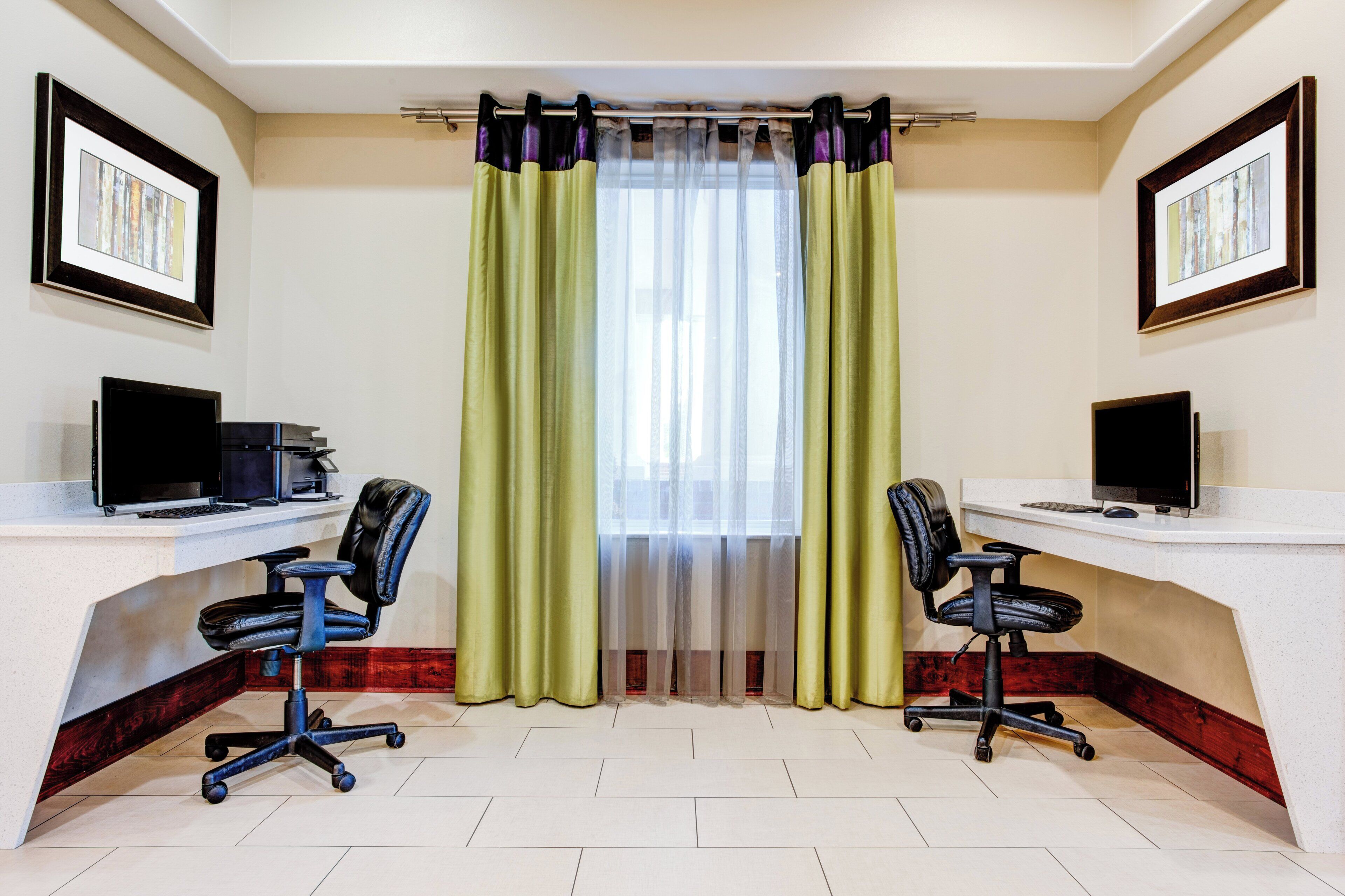 A conference room with two desks, each with a computer and a chair.