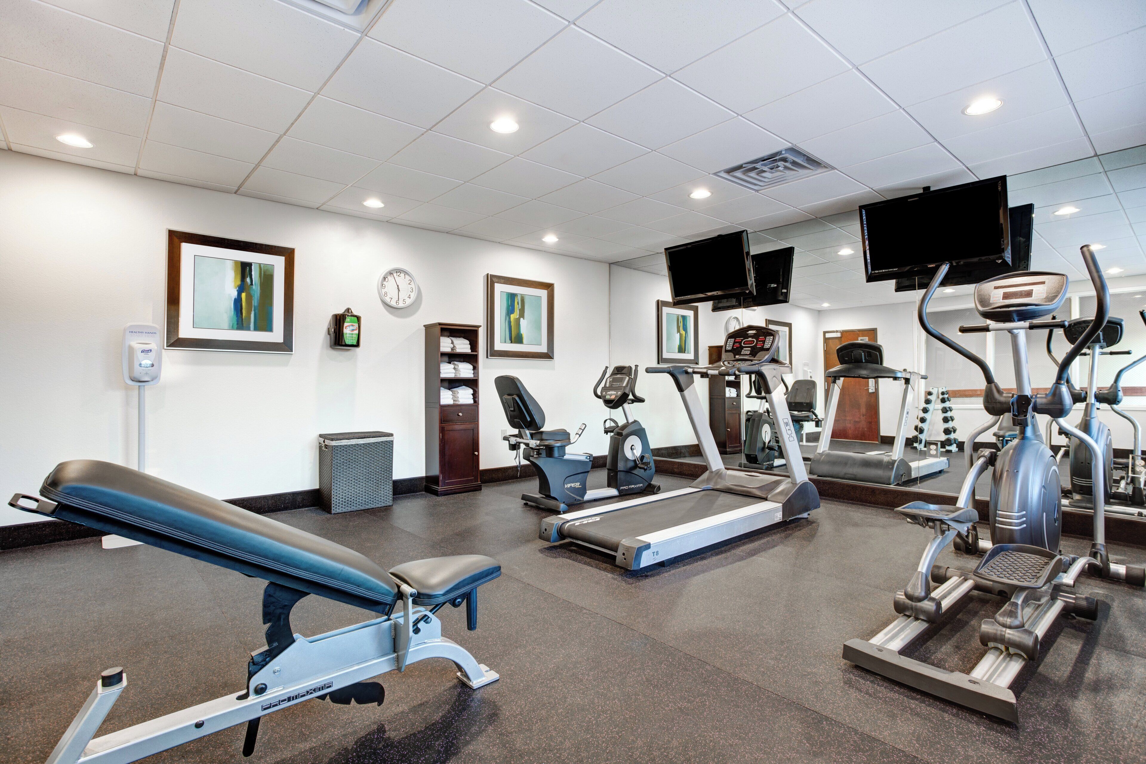 A gym with various exercise equipment, including treadmills, stationary bikes, and a massage chair.