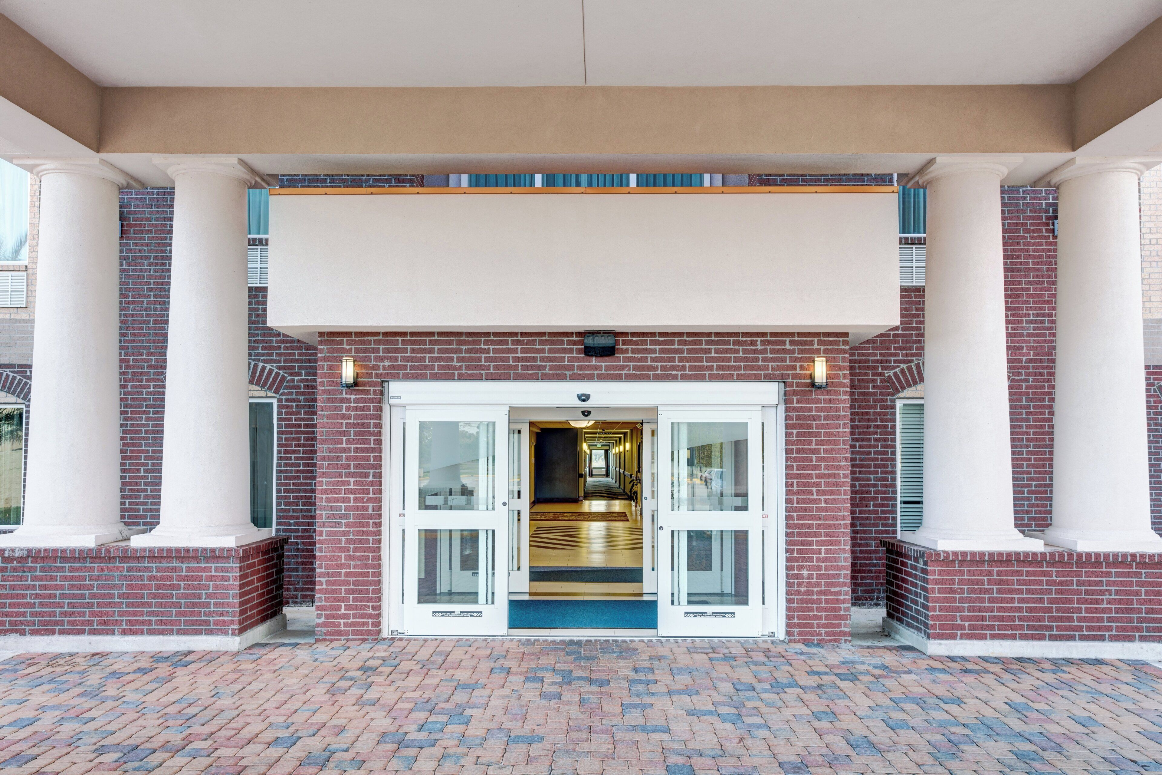 A hotel entrance with a brick facade, white columns, and a double door.