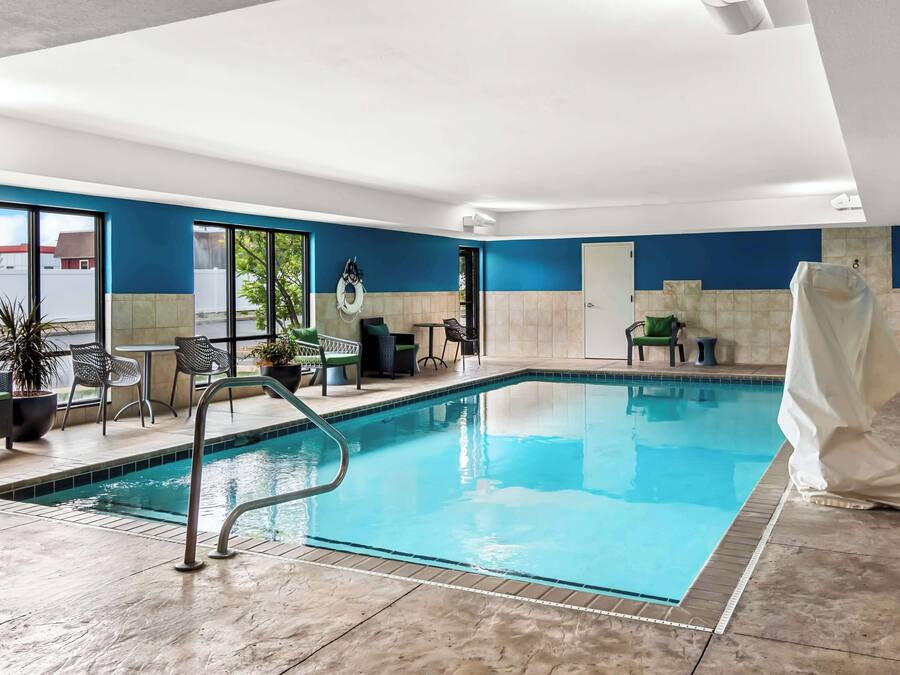 Una piscina interior con agua azul cristalina, rodeada de paredes con azulejos e iluminación empotrada en el techo.