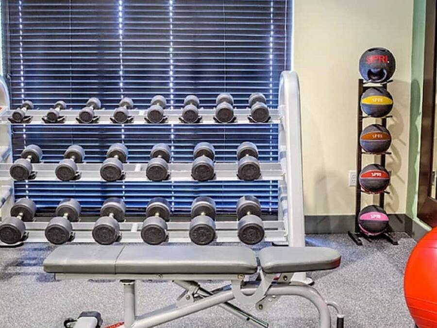 Ein Fitnessraum mit Reihen von Kurzhanteln, einer Bank und Trainingsbällen.