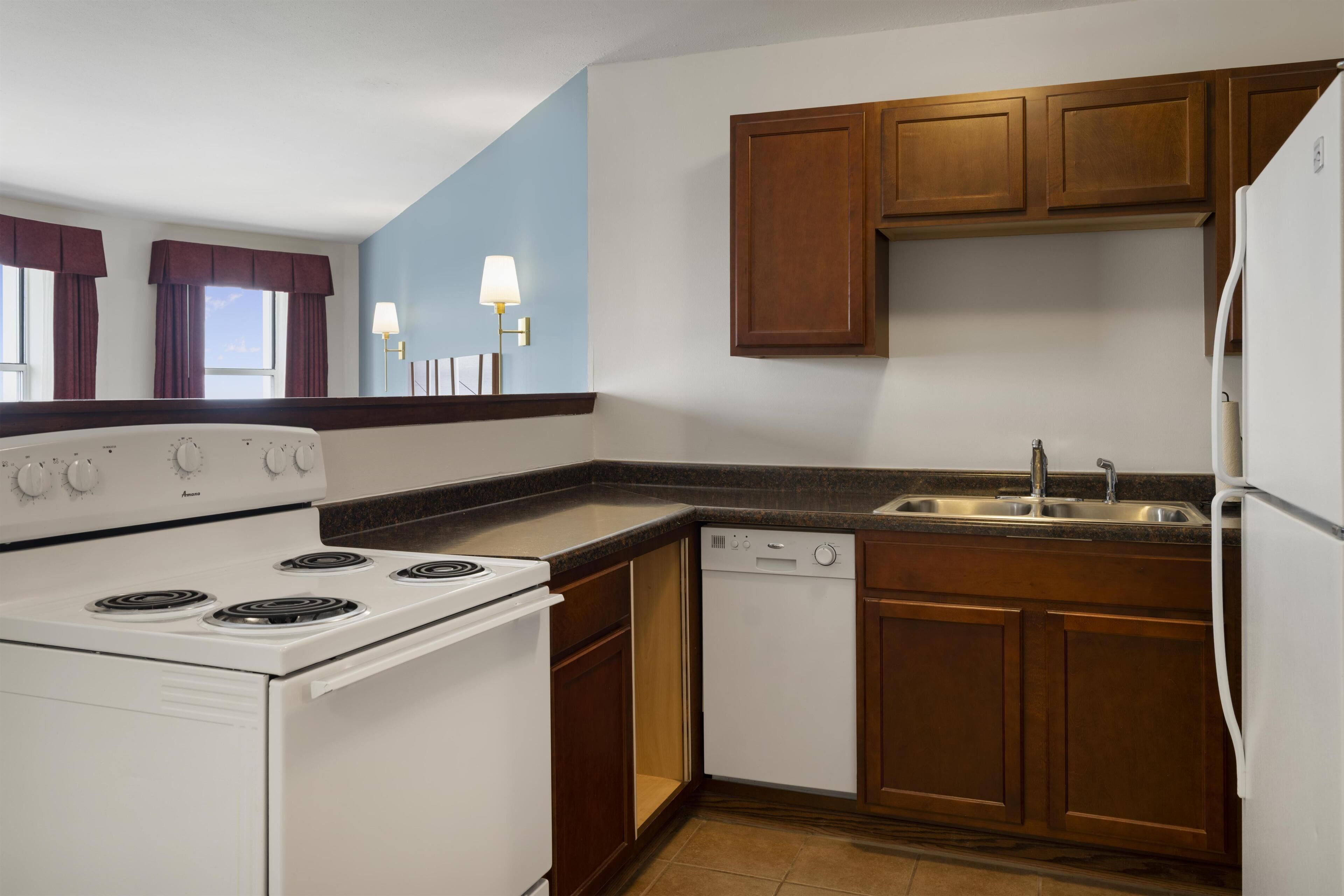 A kitchen with a stove, dishwasher, and cabinets.