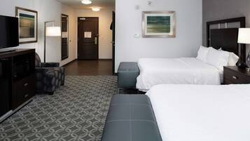 A hotel room with two beds, a desk, a TV, and a patterned carpet.