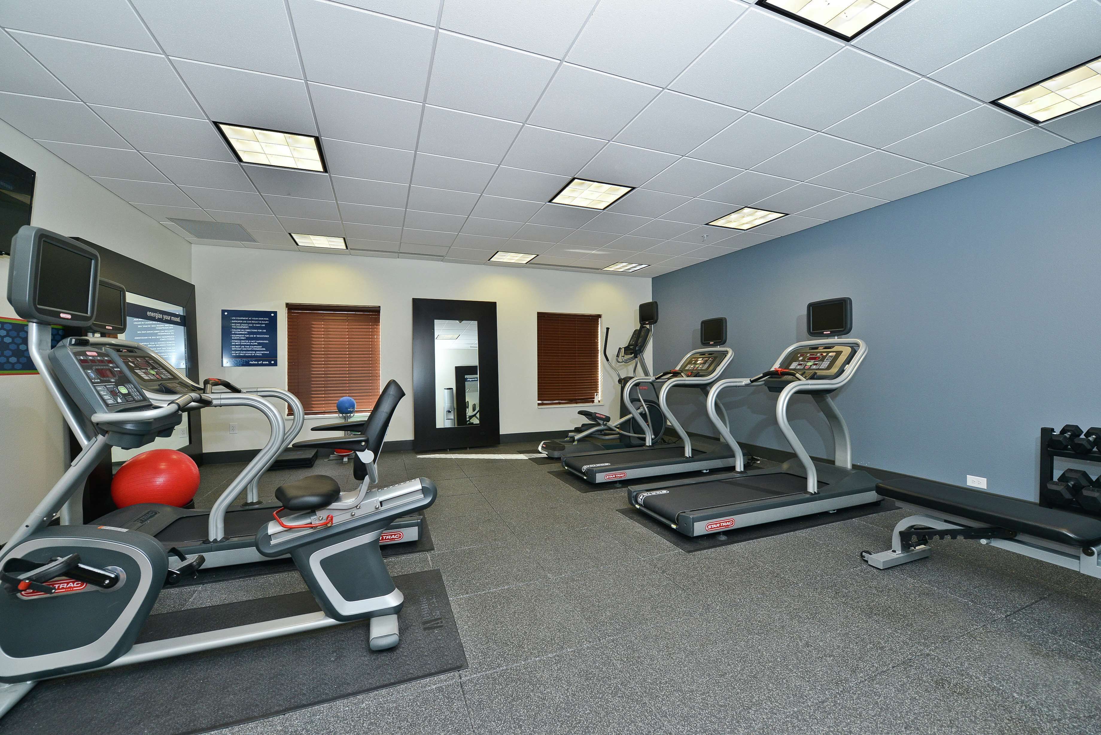 A gym with treadmills, a stationary bike, and a red exercise ball.