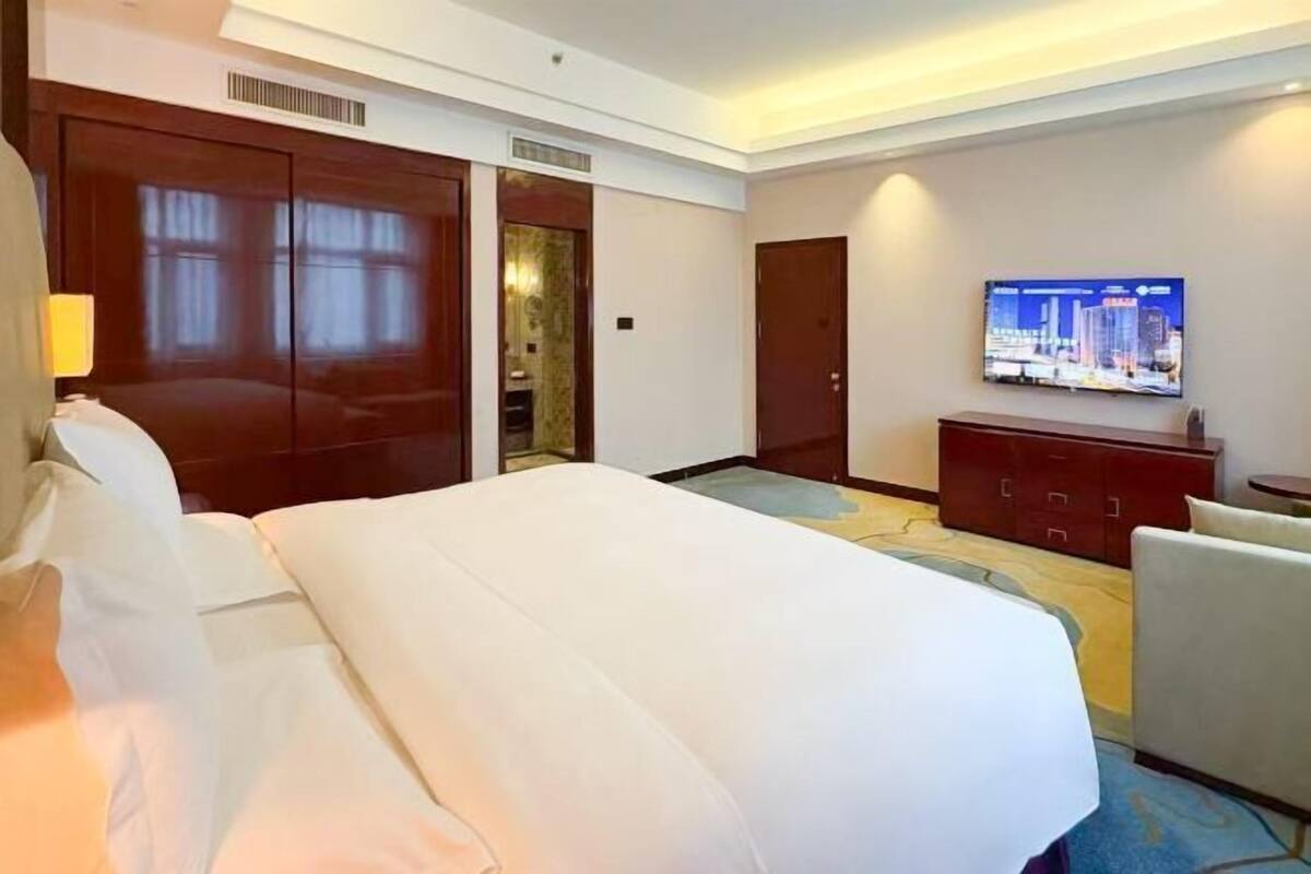 A hotel room with a large bed, a television, a wardrobe, and a desk.