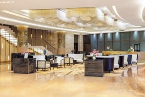 A spacious lobby with a reception desk, seating area, and a staircase.