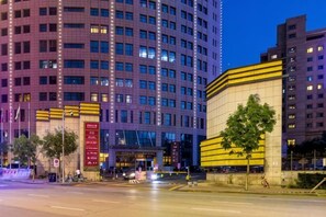 A multi-story building with a modern architectural design, featuring a prominent entrance with a glass facade and a yellow accent wall.