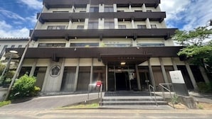 Un edificio de varios pisos con techo plano, ventanas amplias y una entrada central con escalones.