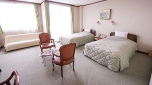 Une chambre d’hôtel avec deux lits, un canapé, une chaise et une petite table.