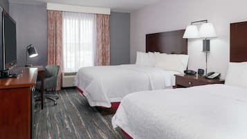 A hotel room with two beds, a desk with a computer, a TV, a lamp, and a telephone.