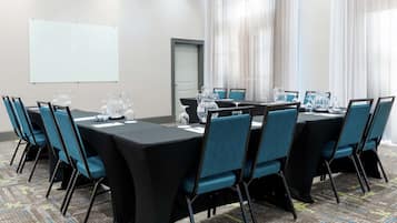 Une salle de conférence avec une longue table, des chaises et un tableau blanc.
