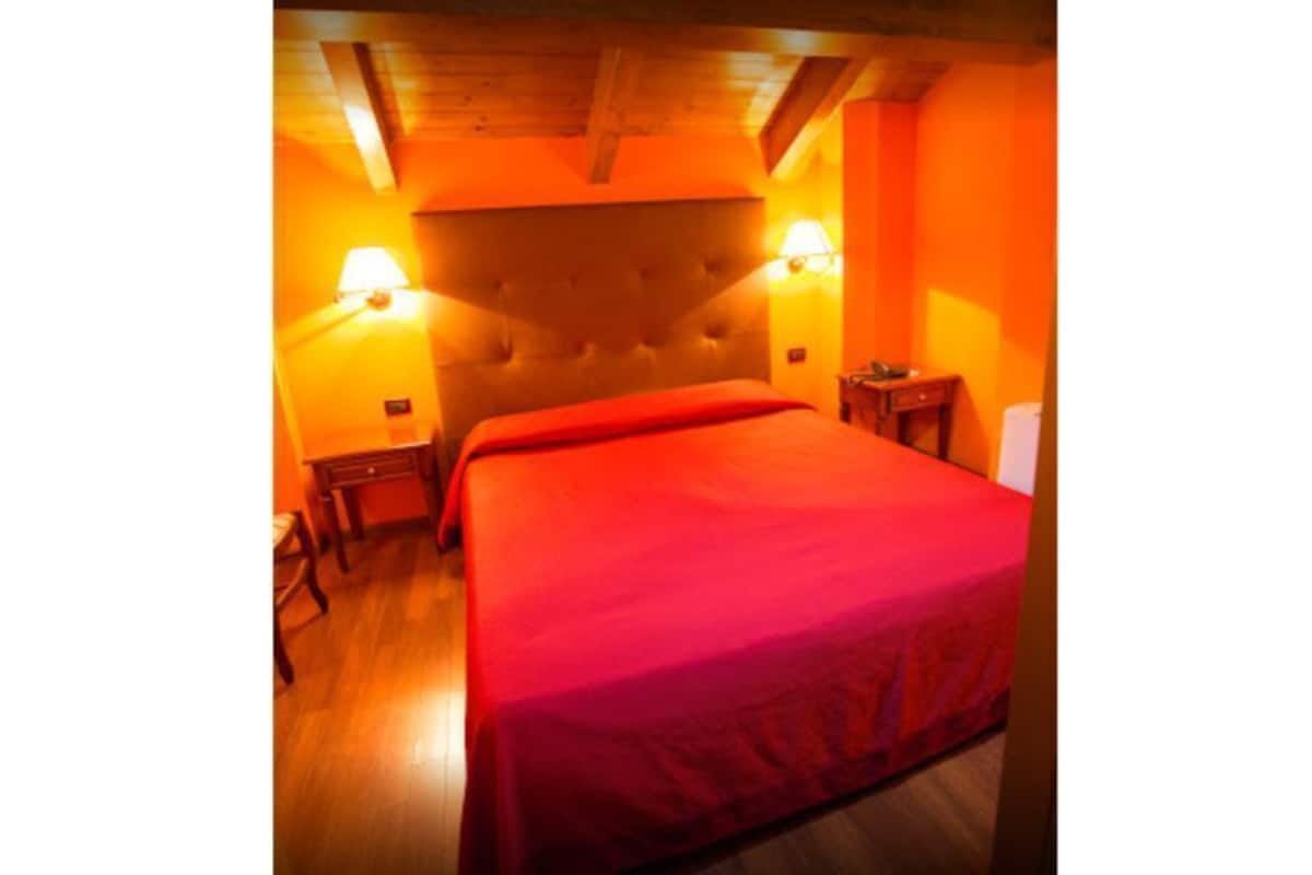 A room with a bed, two bedside tables, and a nightstand.