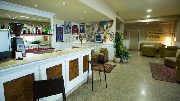 A spacious living area with a bar, multiple seating options, and a variety of wall decorations. - Hotel Vazzana (Volpiano)