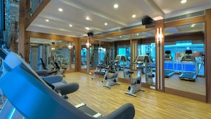 Un gimnasio con equipamiento de ejercicio, espejos y suelo de madera.