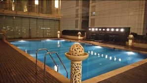 Una piscina interior con cubierta de madera, un pilar decorativo y una zona de estar junto a la piscina.