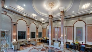 Un lobby amplio con un diseño circular en el suelo, techos altos y un candelabro.