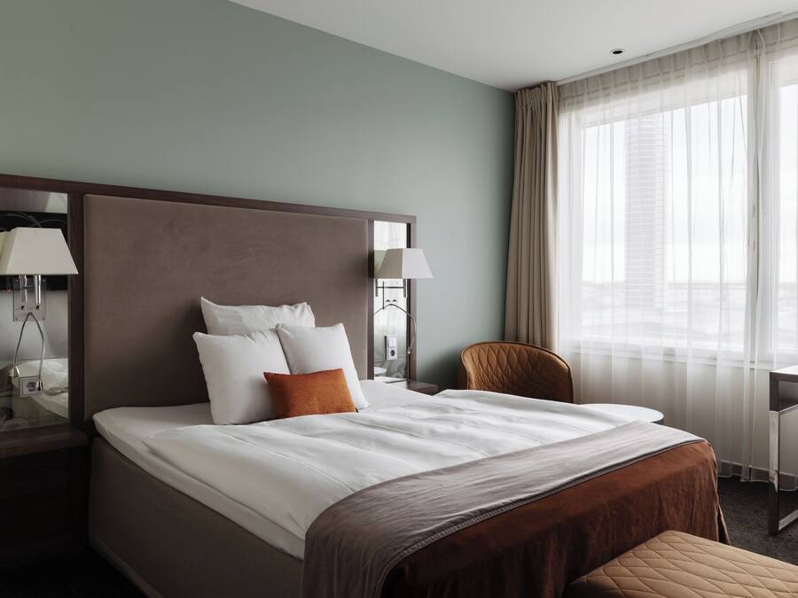 A hotel room with a large bed, a desk, and a chair.