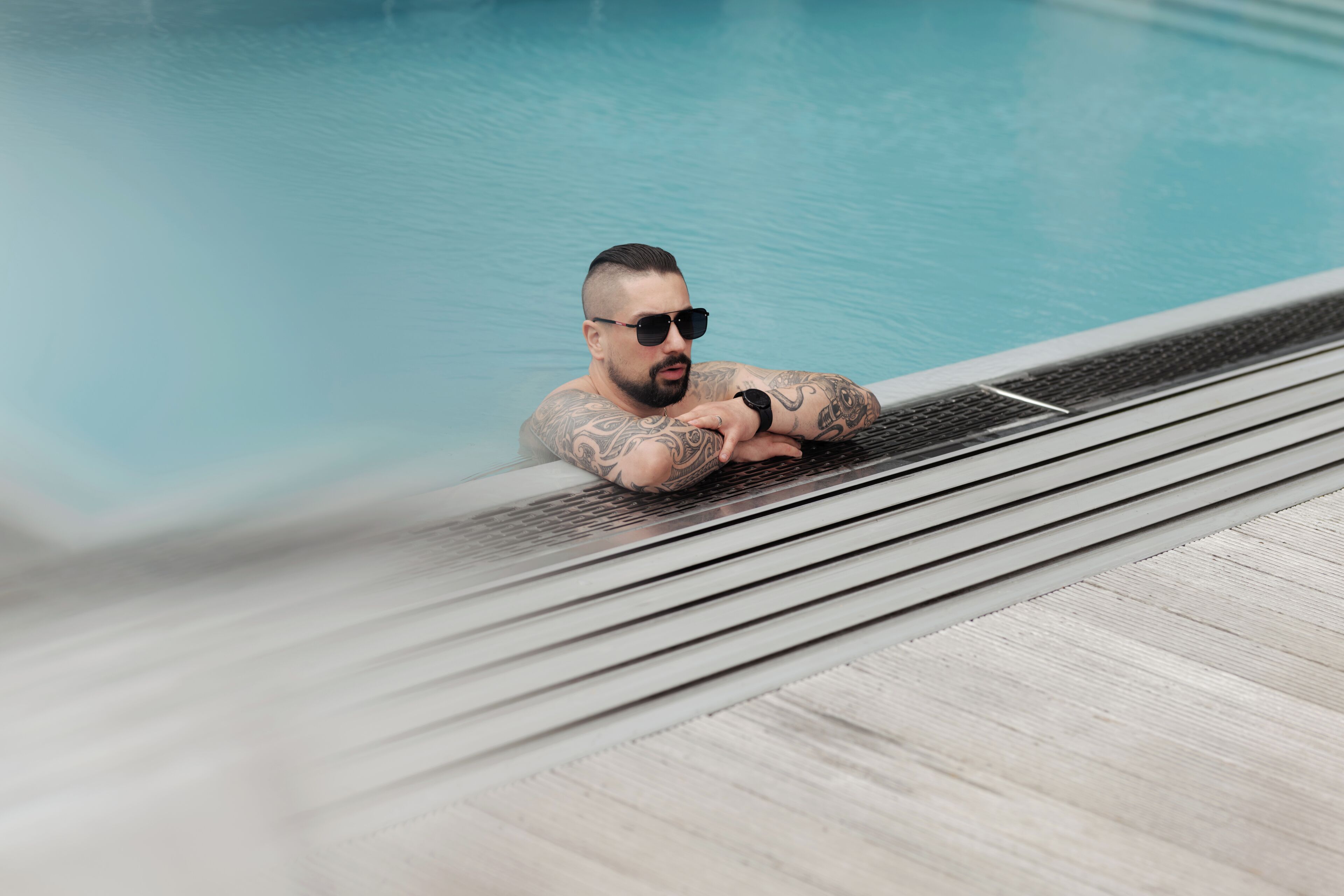 En person som kopplar av vid en pool med ett trädäck.