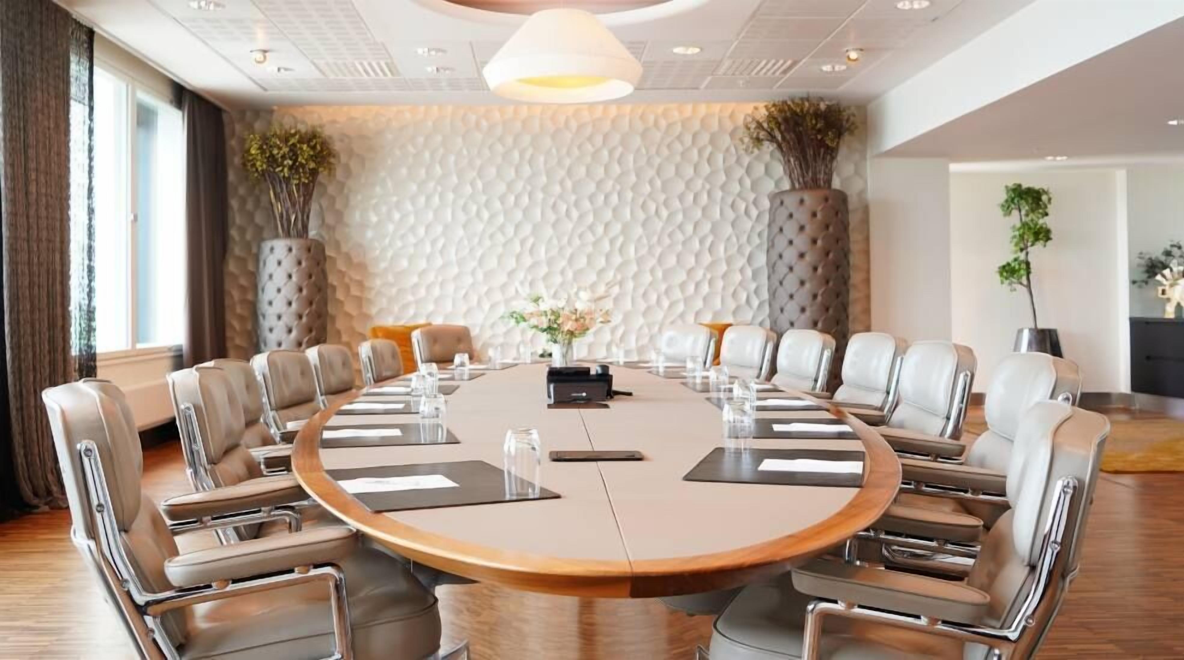 A conference room with a round table, leather chairs, and a textured wall.